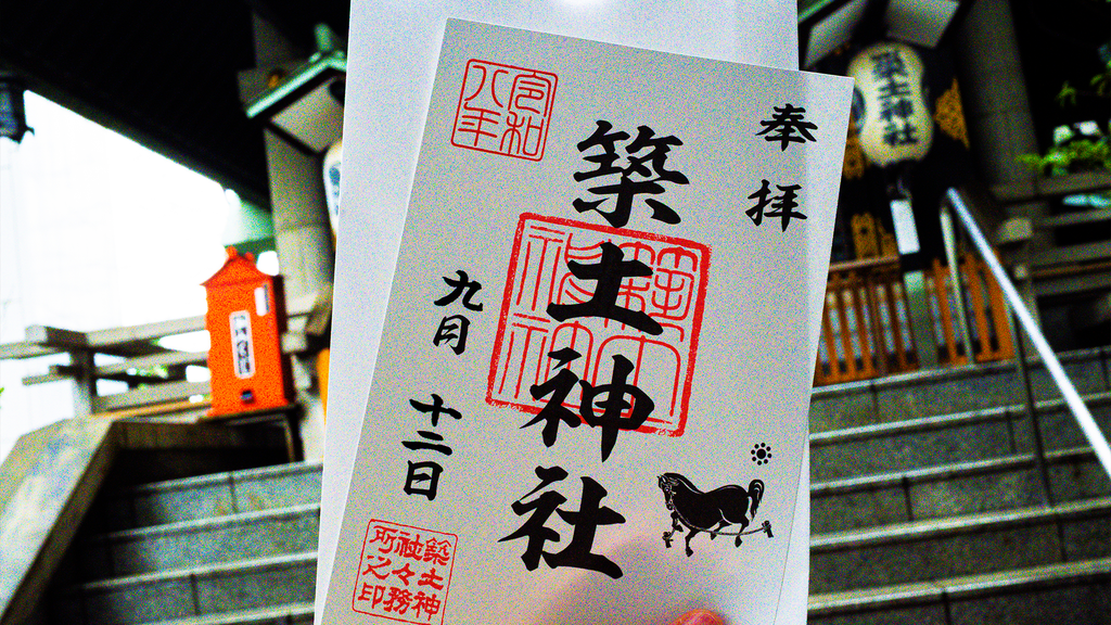 Goshuin from Tsukudo Shrine in Tokyo held in front of the shrine